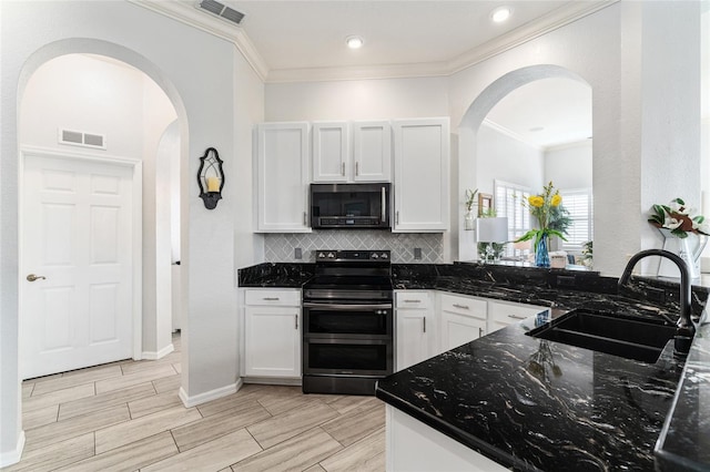 kitchen featuring sink, range with electric stovetop, white cabinets, dark stone countertops, and backsplash