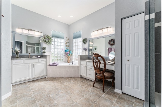 bathroom with a relaxing tiled bath, vanity, and tile flooring