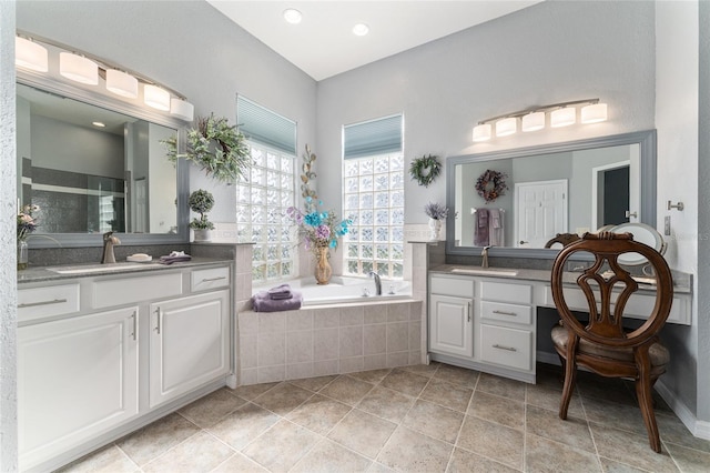 bathroom featuring tiled bath, dual vanity, and tile flooring