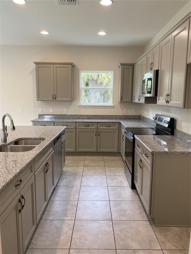 kitchen with stainless steel appliances, light tile flooring, and light stone counters