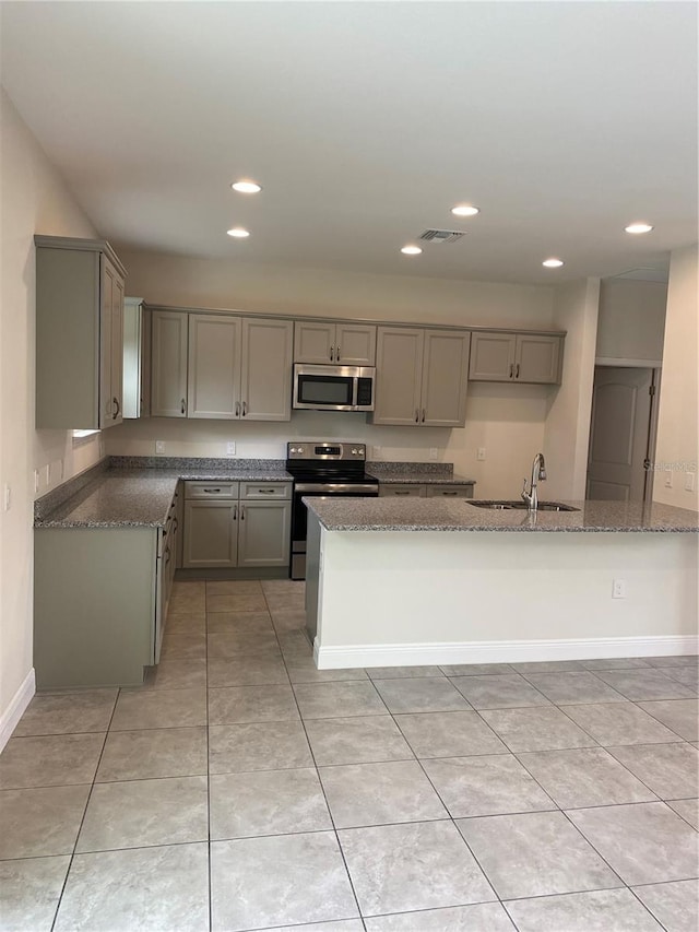 kitchen featuring dark stone counters, stainless steel appliances, light tile floors, and sink