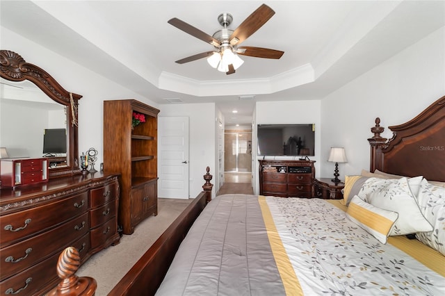 bedroom with ornamental molding, a tray ceiling, ceiling fan, ensuite bathroom, and light colored carpet