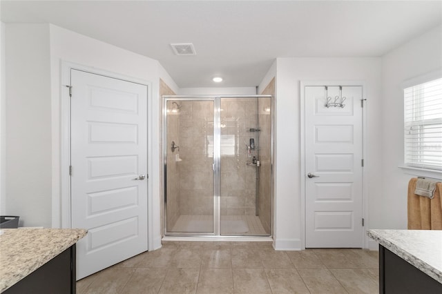 bathroom with a shower with door, tile flooring, and vanity