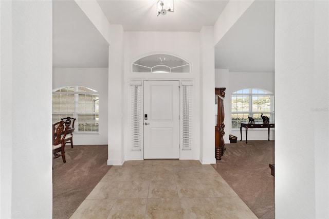 foyer entrance featuring light carpet and a chandelier