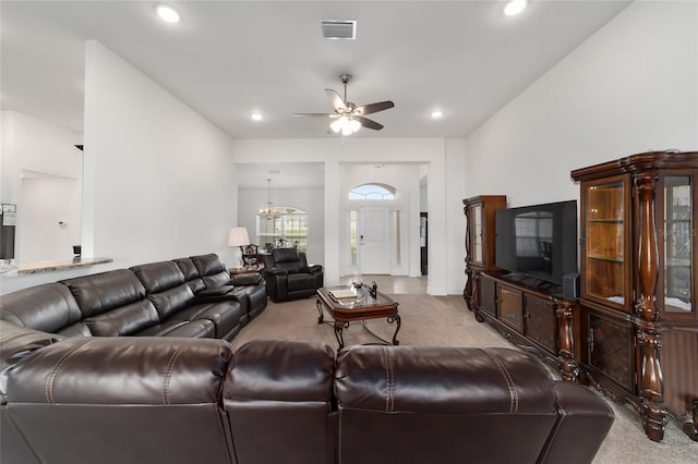 carpeted living room featuring ceiling fan with notable chandelier