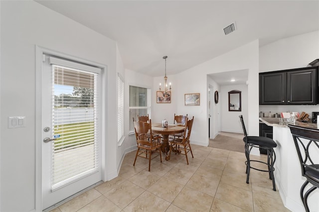 dining room featuring light tile flooring, vaulted ceiling, and a notable chandelier