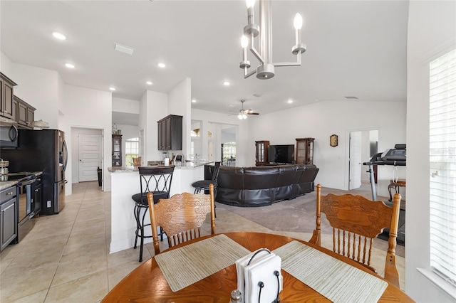 dining room featuring lofted ceiling, light tile floors, and ceiling fan with notable chandelier