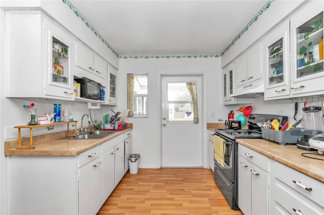 kitchen featuring black appliances, light hardwood / wood-style floors, sink, white cabinets, and a textured ceiling