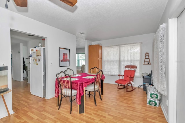 dining area with a textured ceiling, ceiling fan, and light hardwood / wood-style flooring