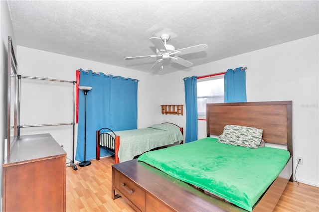 bedroom with light hardwood / wood-style floors, ceiling fan, and a textured ceiling