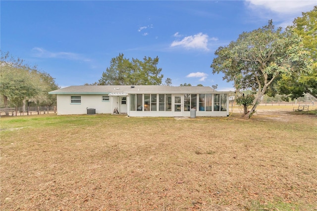 back of house with central AC unit, a sunroom, and a yard