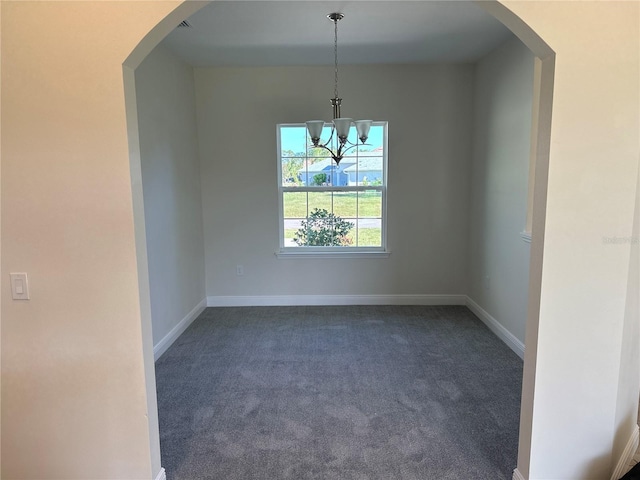 unfurnished room with an inviting chandelier and dark colored carpet