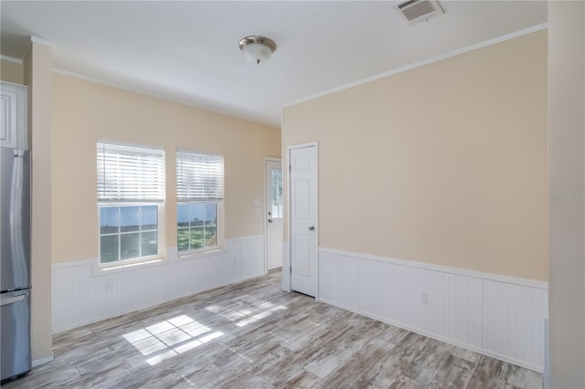 spare room with light wood-type flooring and ornamental molding