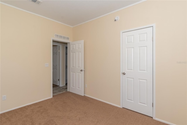 spare room featuring light colored carpet and crown molding