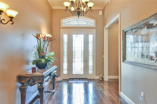 foyer featuring dark wood-type flooring, a chandelier, and ornamental molding