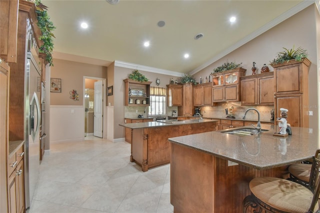 kitchen with ornamental molding, tasteful backsplash, sink, a breakfast bar area, and a large island