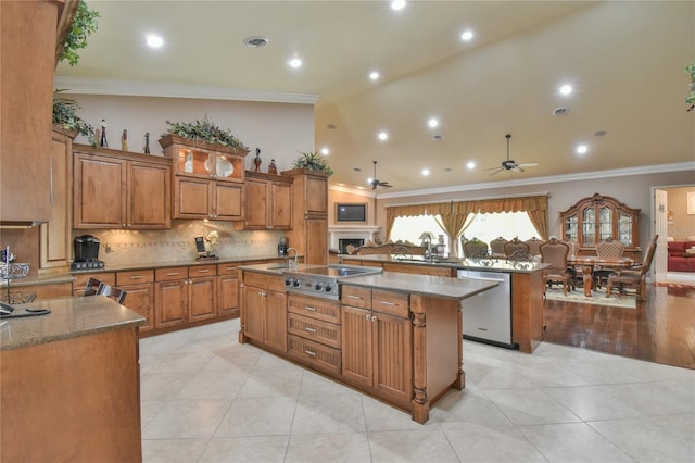 kitchen with light hardwood / wood-style floors, an island with sink, stainless steel appliances, ornamental molding, and ceiling fan