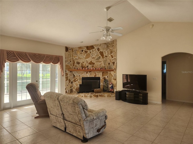 tiled living room with a textured ceiling, a fireplace, ceiling fan, and lofted ceiling