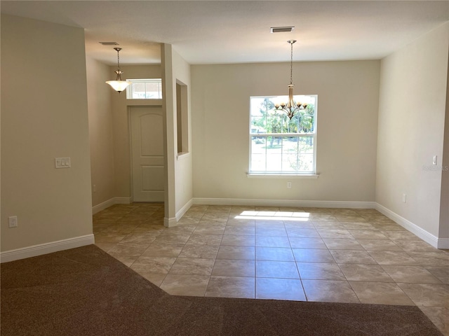 spare room featuring plenty of natural light, light tile floors, and a notable chandelier