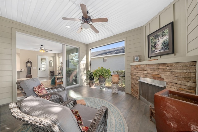 sunroom with a stone fireplace and ceiling fan