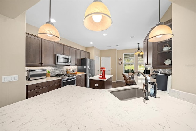 kitchen featuring appliances with stainless steel finishes, hanging light fixtures, dark brown cabinetry, and sink