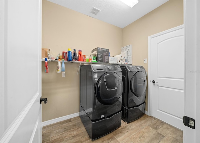 washroom featuring washing machine and clothes dryer and light wood-type flooring