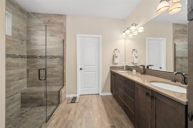 bathroom featuring an enclosed shower, oversized vanity, hardwood / wood-style floors, and dual sinks