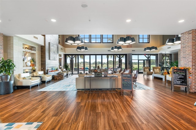 living room featuring a high ceiling, brick wall, and dark hardwood / wood-style floors