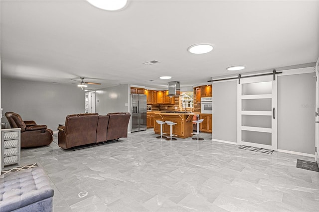 living room featuring a barn door, light tile floors, built in features, and ceiling fan