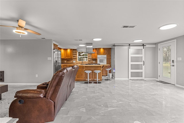 living room featuring a barn door, light tile floors, and ceiling fan