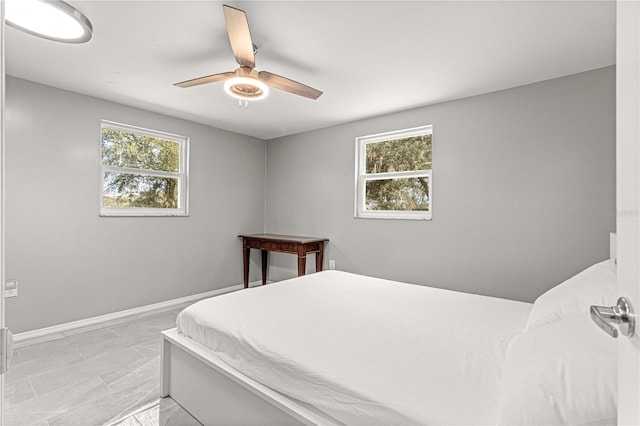 tiled bedroom with ceiling fan and multiple windows