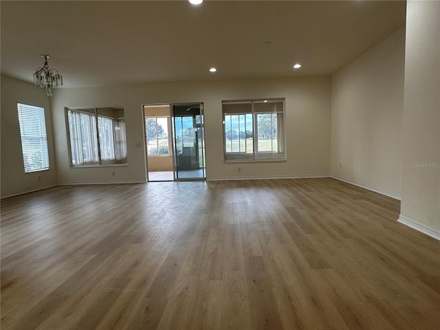 unfurnished room with an inviting chandelier and light hardwood / wood-style flooring