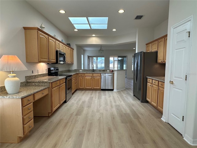 kitchen featuring appliances with stainless steel finishes, light hardwood / wood-style floors, a skylight, kitchen peninsula, and sink