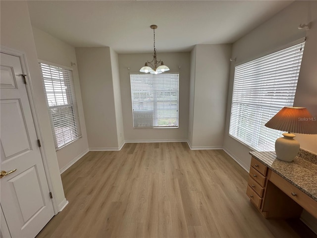 unfurnished dining area with a notable chandelier and light hardwood / wood-style flooring