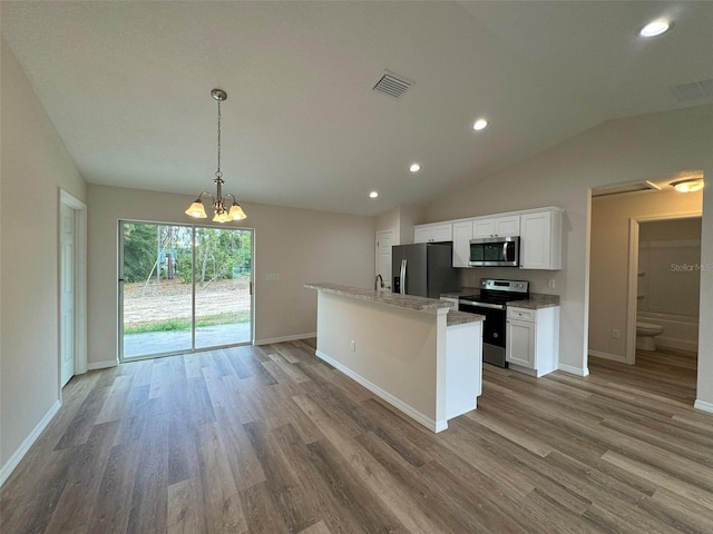 kitchen with lofted ceiling, hardwood / wood-style floors, stainless steel appliances, white cabinets, and decorative light fixtures