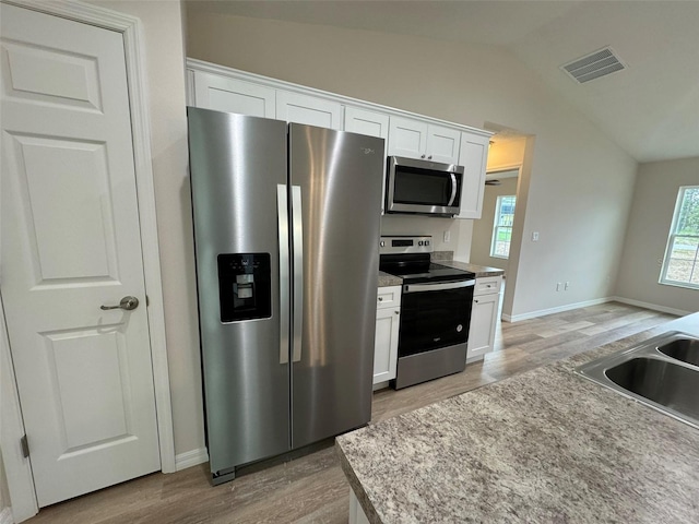 kitchen featuring stainless steel appliances, white cabinetry, lofted ceiling, and hardwood / wood-style floors