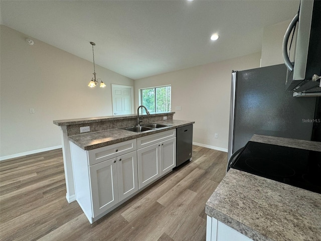 kitchen featuring sink, white cabinets, hanging light fixtures, stainless steel appliances, and a center island with sink