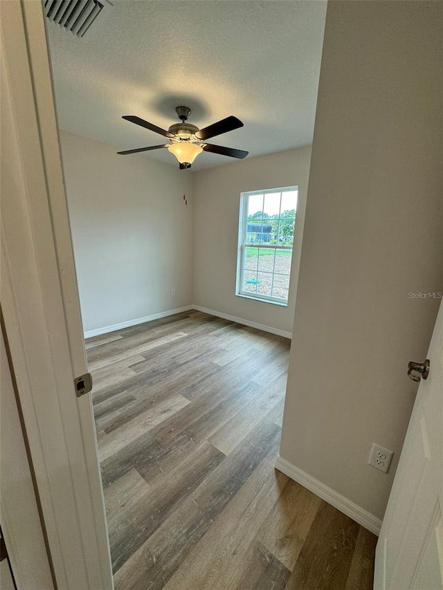 spare room with ceiling fan, light hardwood / wood-style flooring, and a textured ceiling