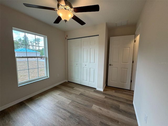 unfurnished bedroom with hardwood / wood-style floors, a closet, and ceiling fan