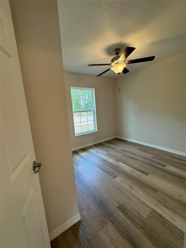 empty room featuring ceiling fan, wood-type flooring, and a textured ceiling