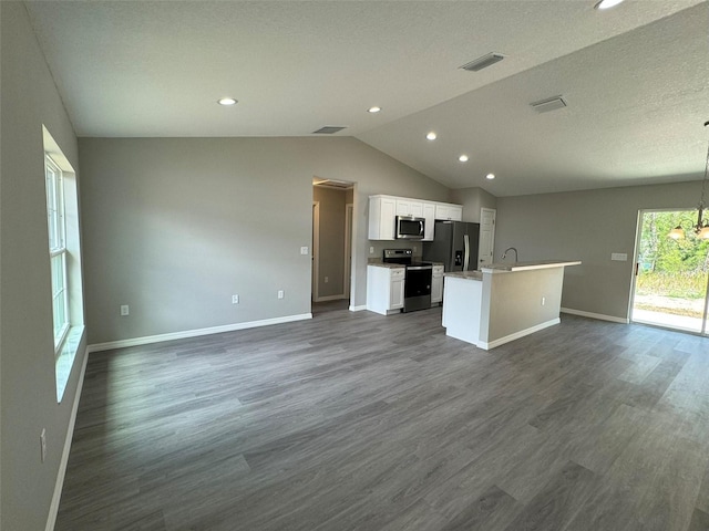 kitchen with appliances with stainless steel finishes, dark hardwood / wood-style floors, white cabinetry, lofted ceiling, and a center island with sink