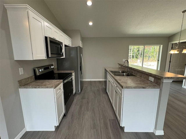 kitchen featuring appliances with stainless steel finishes, dark hardwood / wood-style floors, white cabinetry, sink, and hanging light fixtures