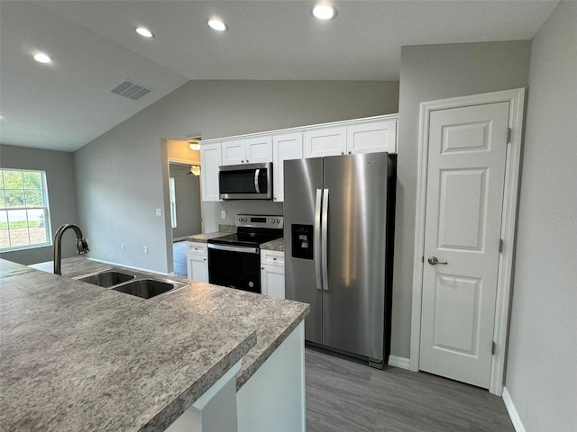 kitchen featuring lofted ceiling, sink, appliances with stainless steel finishes, light hardwood / wood-style floors, and white cabinets