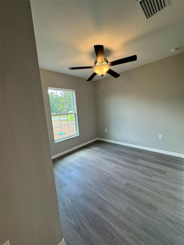 empty room with dark hardwood / wood-style flooring, ceiling fan, and a textured ceiling