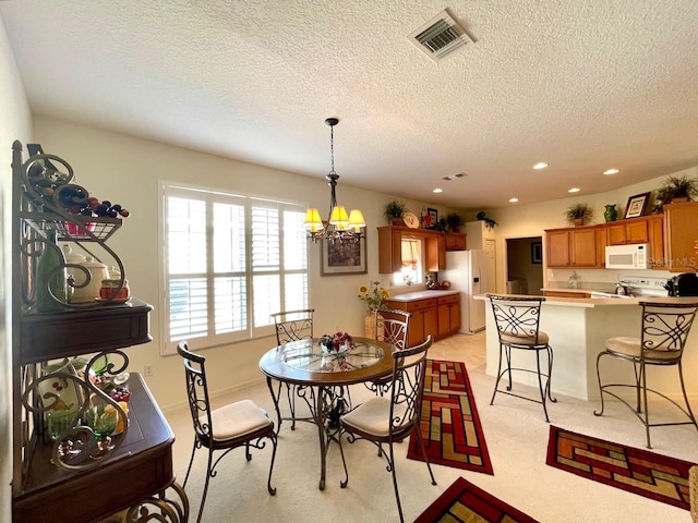 dining space with light colored carpet, a textured ceiling, and a notable chandelier