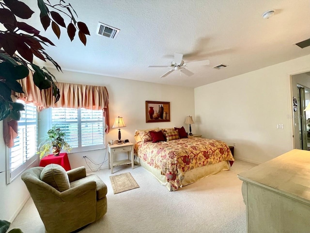 carpeted bedroom with ceiling fan and a textured ceiling