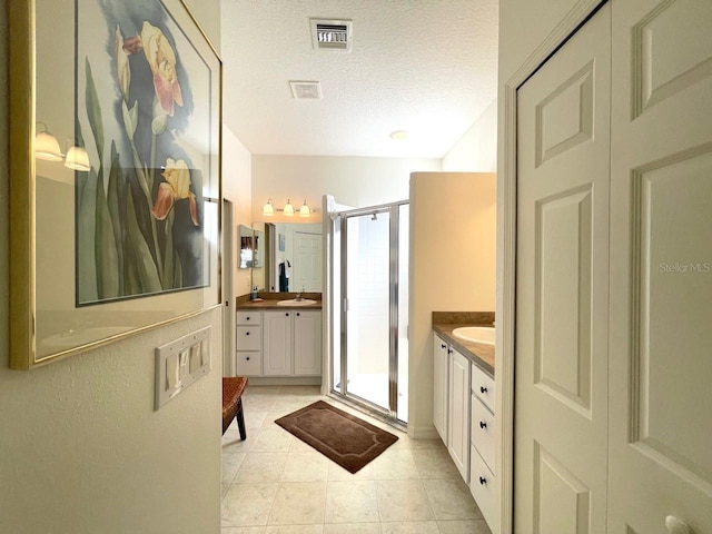 bathroom featuring vanity, tile patterned floors, a textured ceiling, and walk in shower