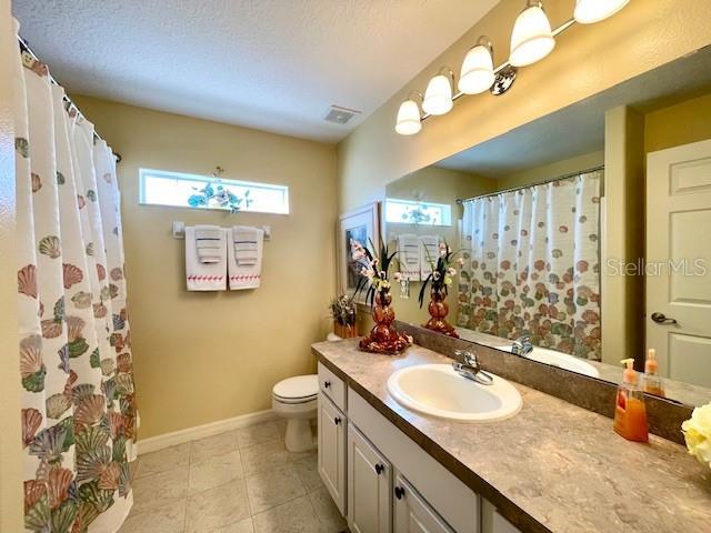 bathroom with vanity, tile patterned floors, a textured ceiling, and toilet