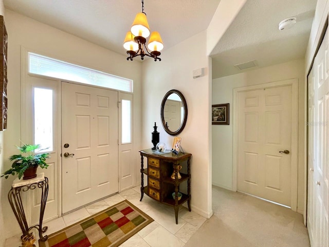 entrance foyer with light colored carpet and an inviting chandelier