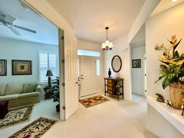 carpeted foyer featuring ceiling fan with notable chandelier